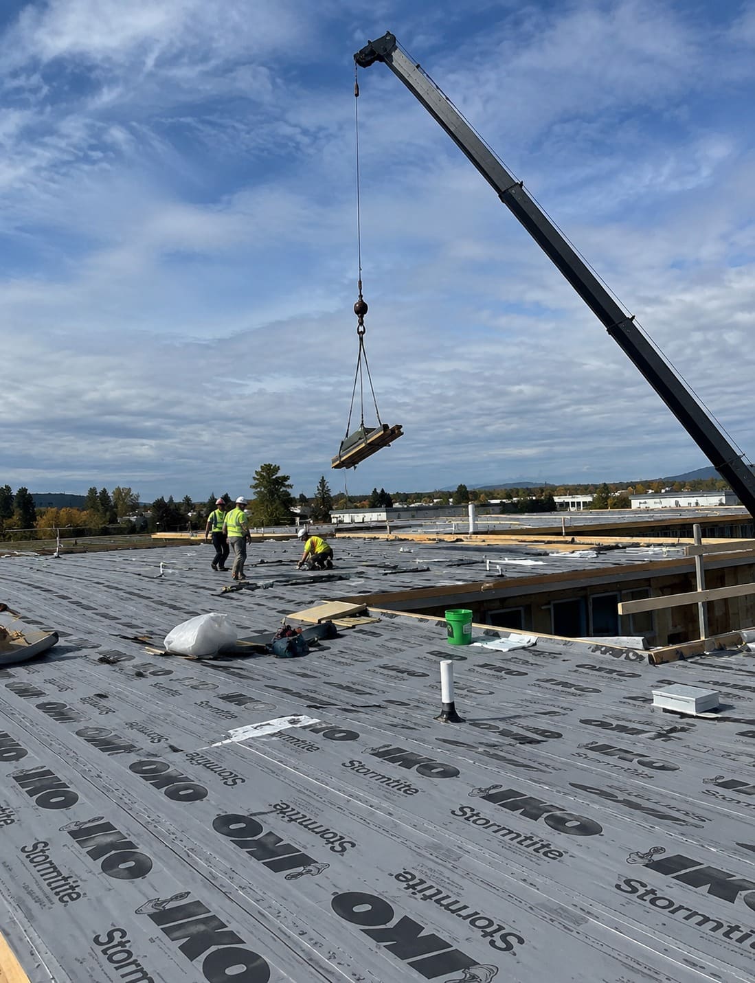 Roofing crew installing underlayment on a large roof in Gresham, Oregon