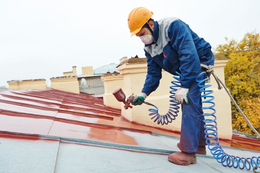 Roofer applying a waterproofing layer to a low-slope roof