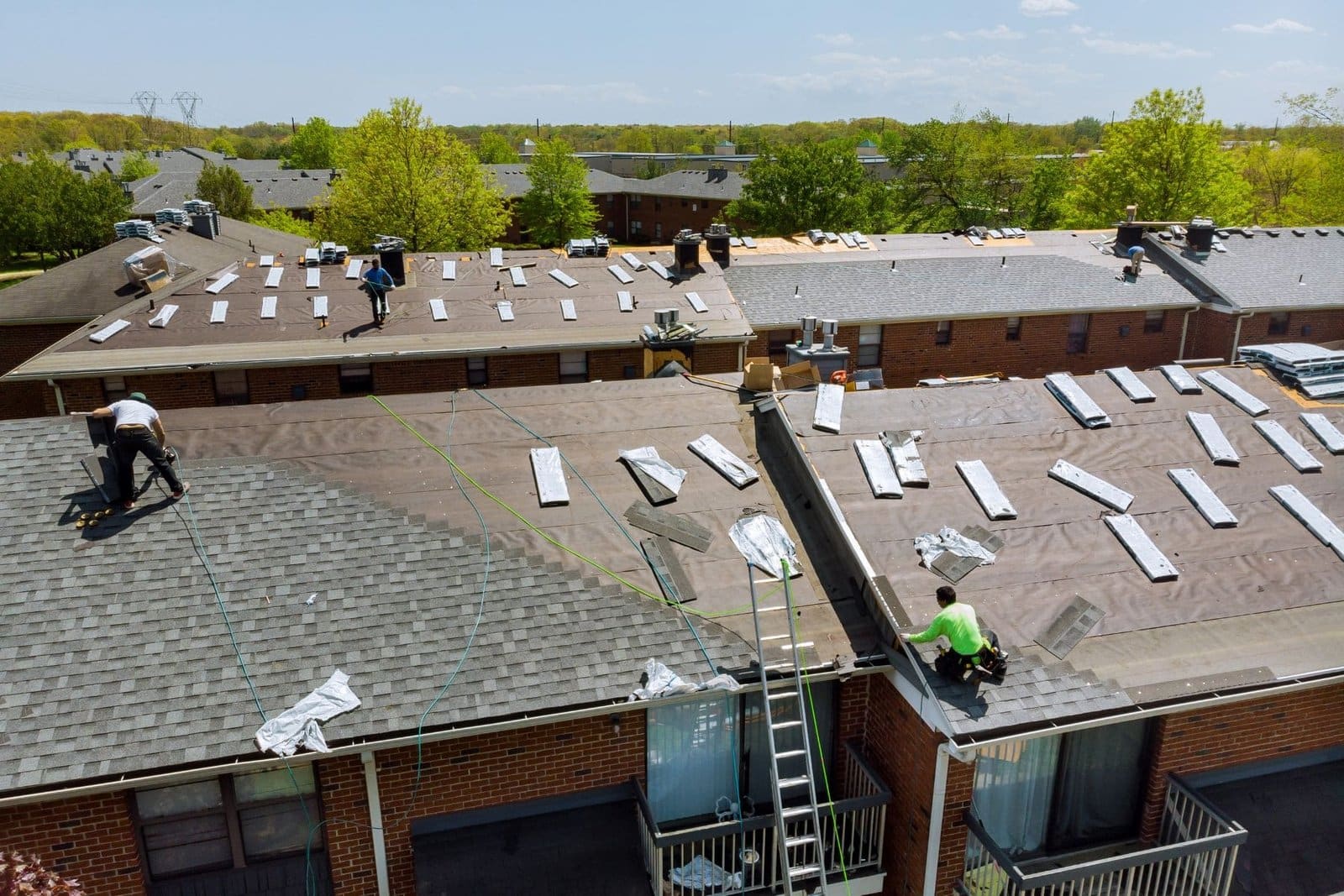 Roofing crew working on low-slope roofs of a multi-unit building