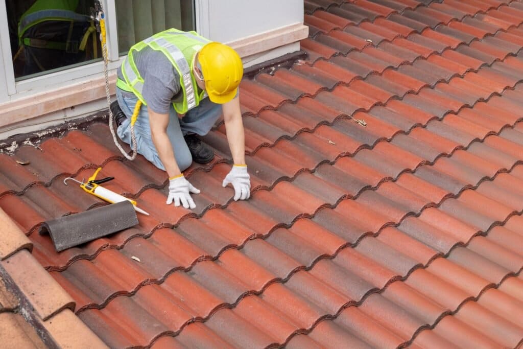 Roofer replacing a damaged roof tile